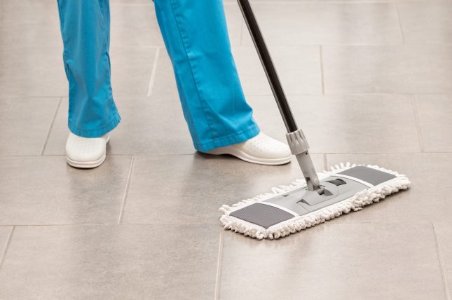 Shot of an unrecognizable woman mopping the office floor