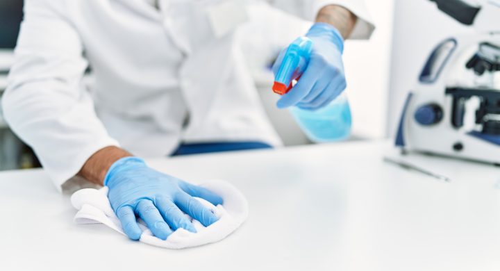 Handsome hispanic man working as scientific cleaning the table at laboratory