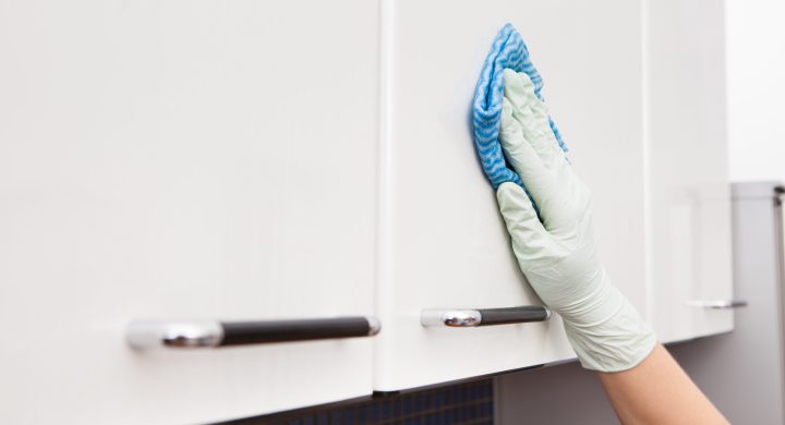 Close-up Of A Woman's Hand Cleaning Cabinet With Cloth